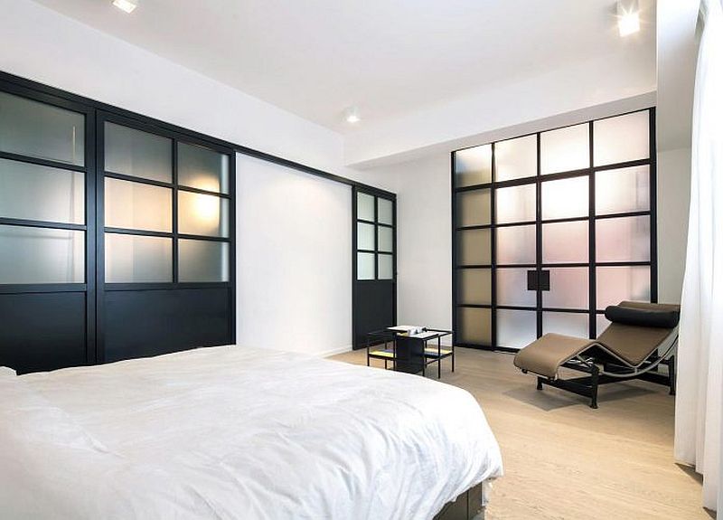 Serene bedroom in white with dark, framed partitions that usher in light