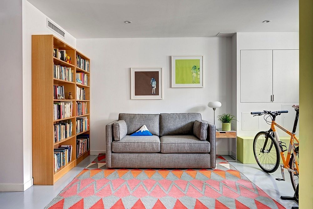 Sitting and media room with comfortable gray couch, colorful rug and a large wooden bookshelf