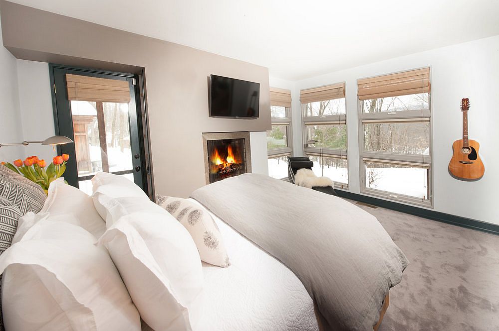 Contemporary bedroom in white with Tv above the fireplace