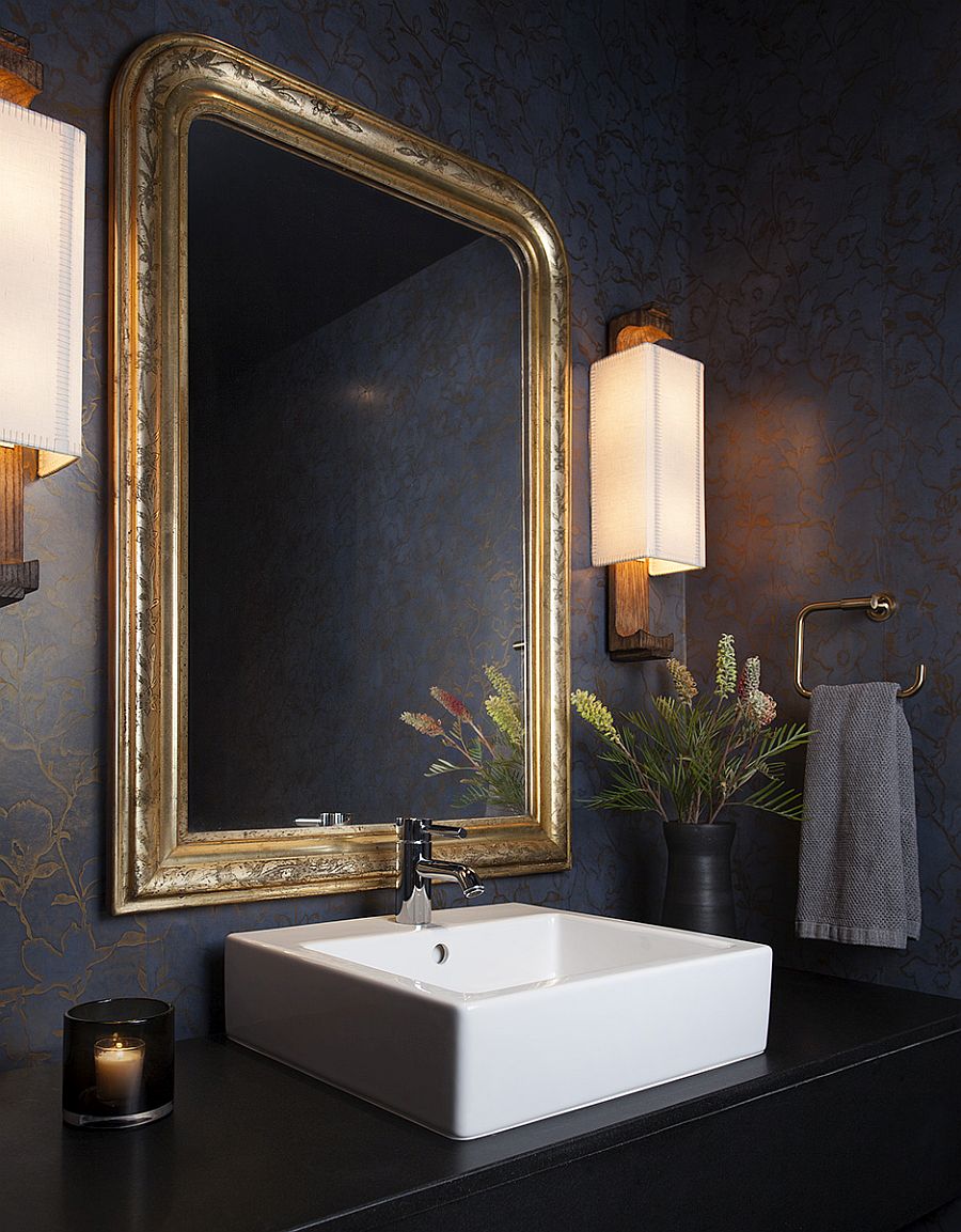 Golden glint of the mirror frame brings sparkle to the dark powder room