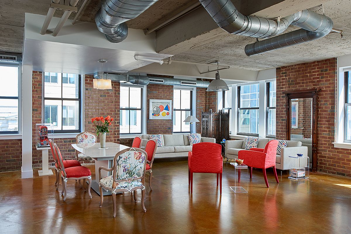 Open plan living area of industrial apartment with colorful chairs