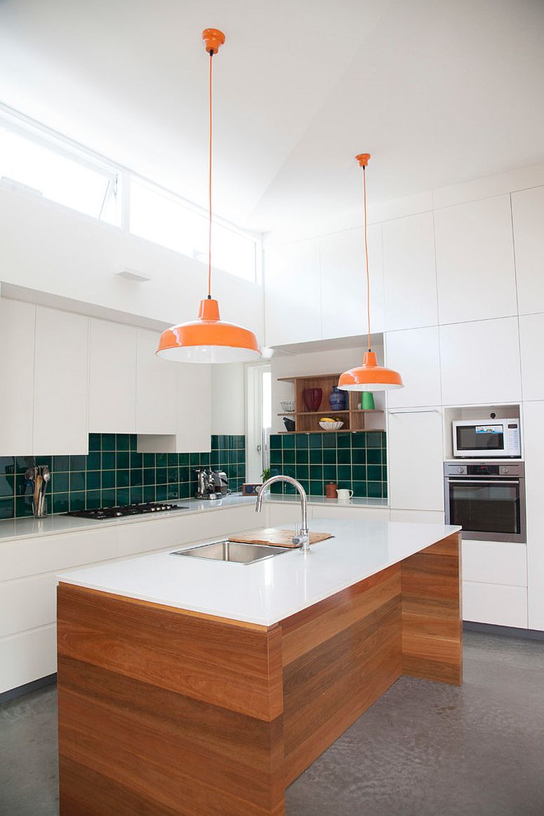 Clean and elegant kitchen design in white with green backsplash and bright orange pendants