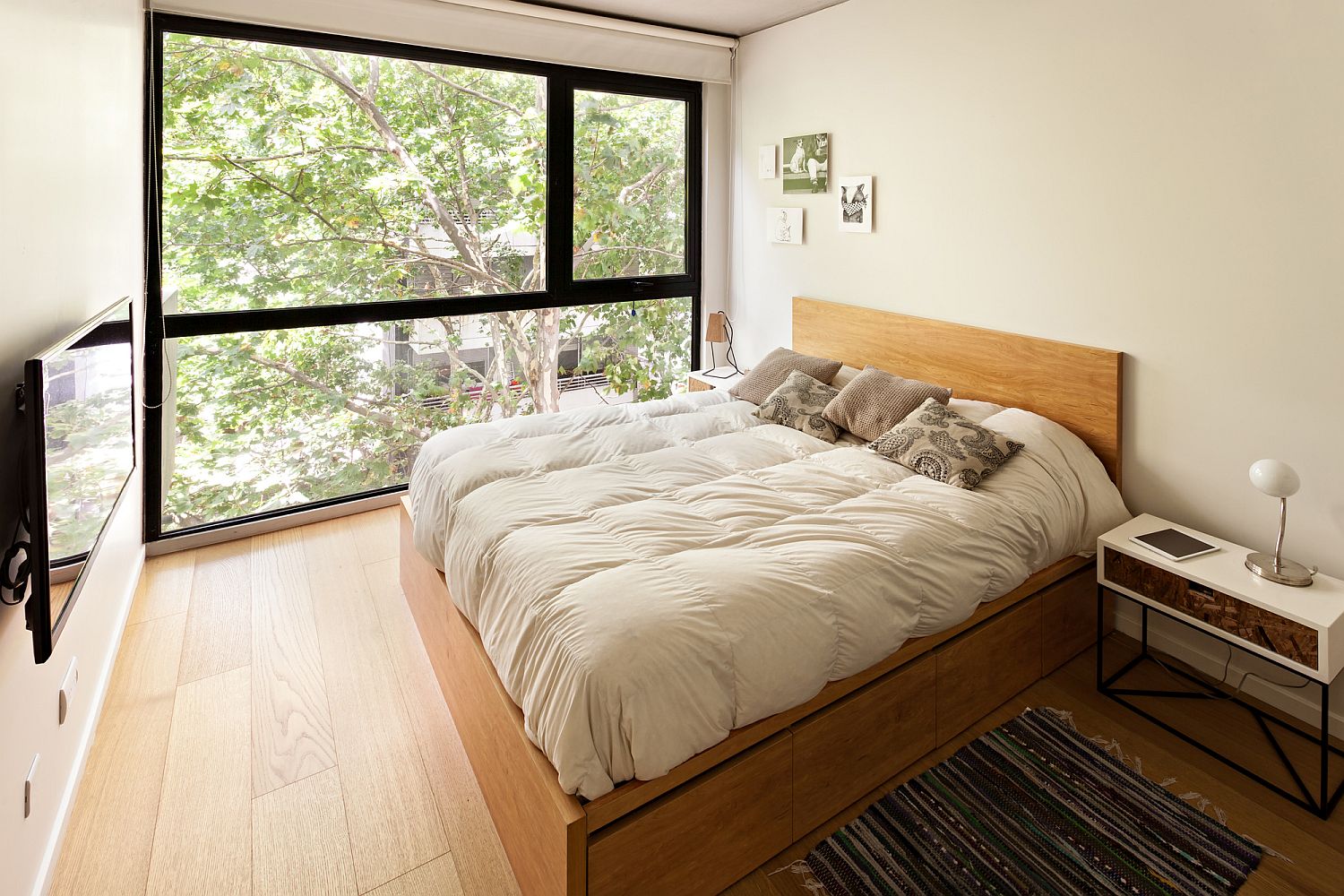 Modern bedroom in white with wooden flooring and a space-savvy bedside table