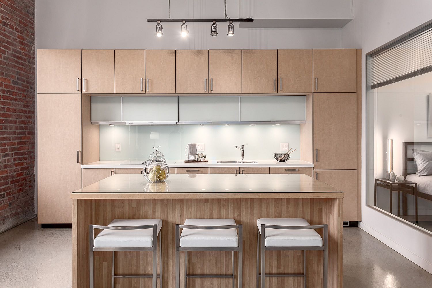 Spacious and light-filled kitchen with brick wall on one side and wooden cabinetry