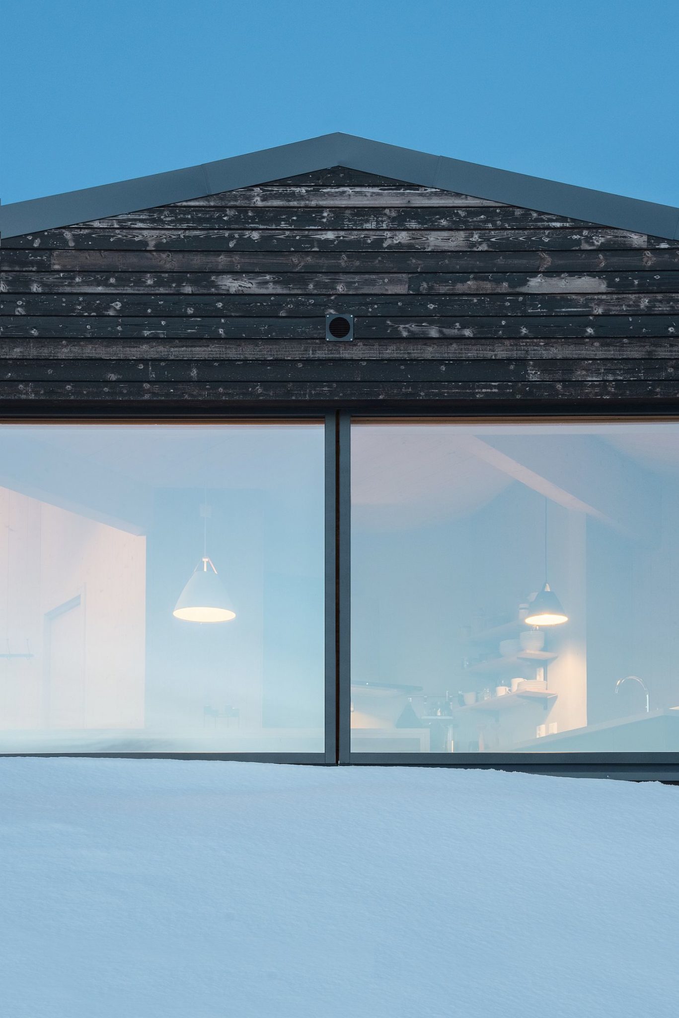 A look into the cabin from the snow-clad slopes around it