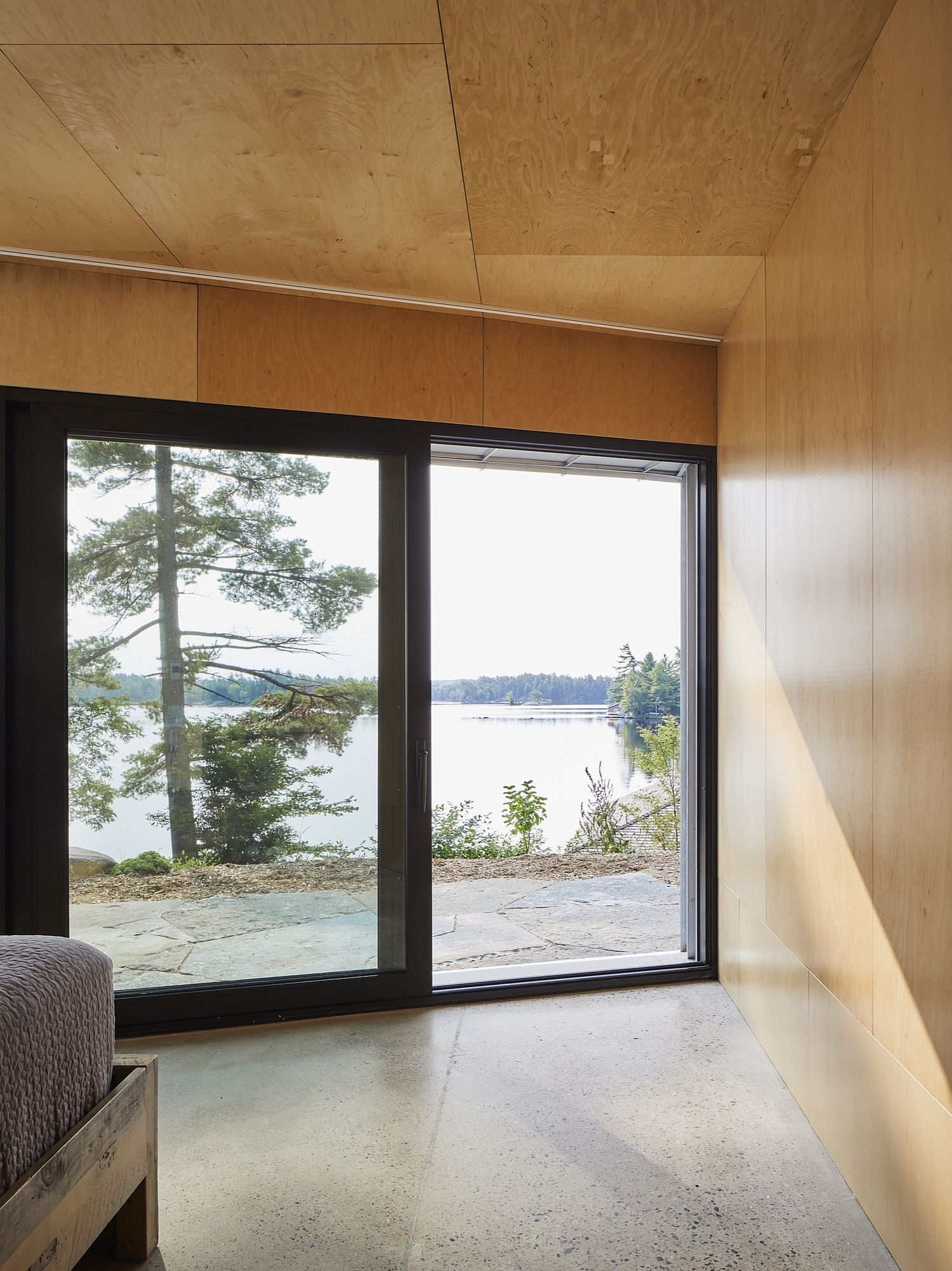 Large glass doors connect the bedroom with a view of the lake outside