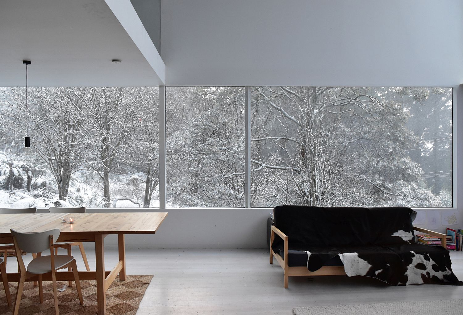 White dining space of the house with a view of the snow-clad landscape outside