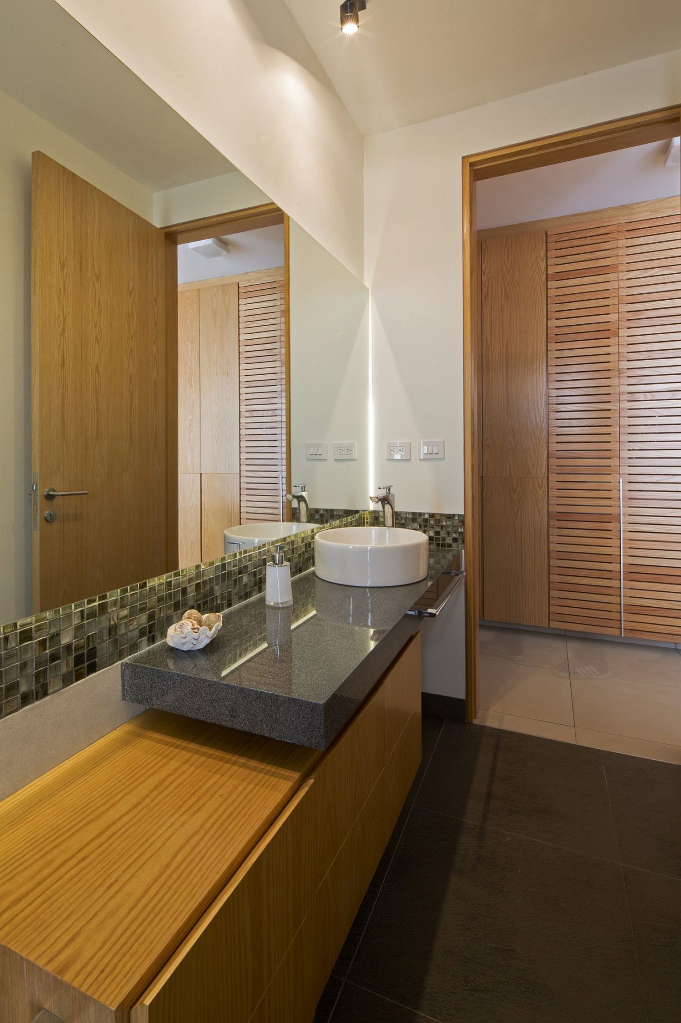 Wooden floating vanity inside the contemporary bathroom with stone countertop