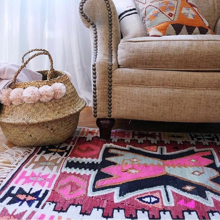 A seagrass belly basket with blush pom poms