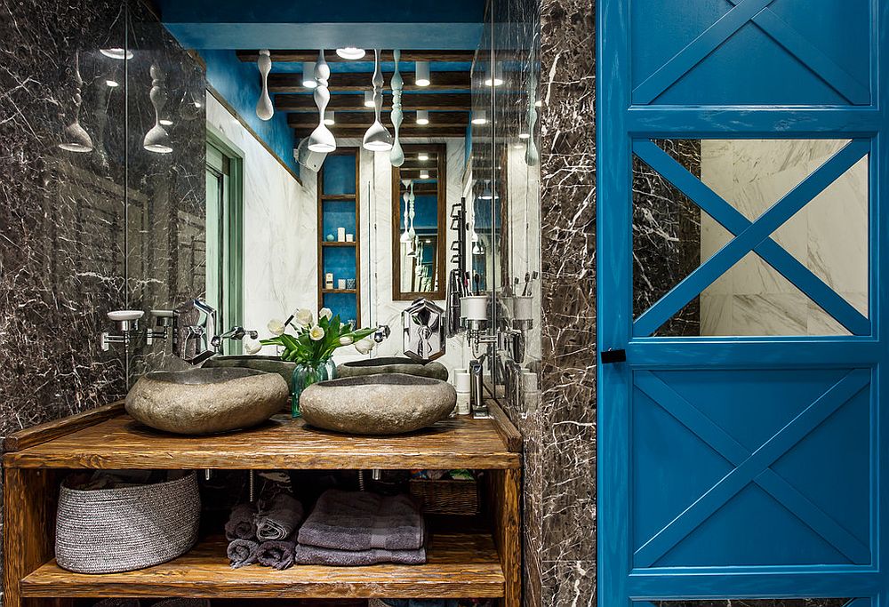 Unique industrial bathroom in stone with wooden vanity and blue backdrop