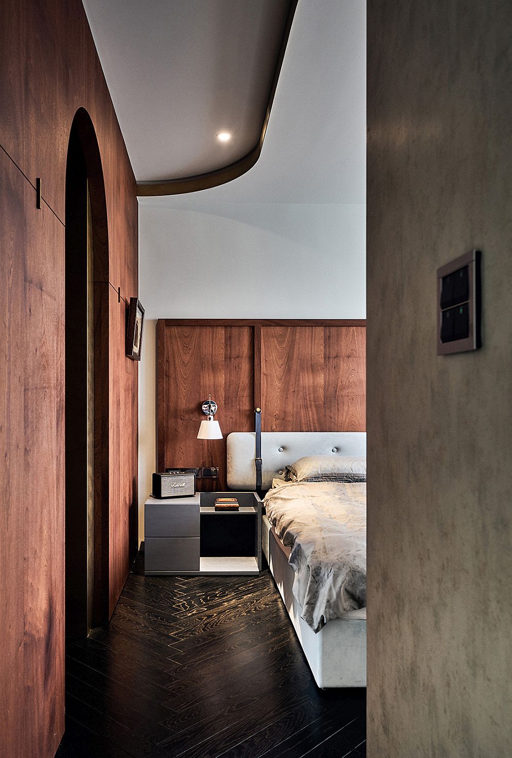Concrete walls and wooden walls sit comfortably next to one another in the bedroom