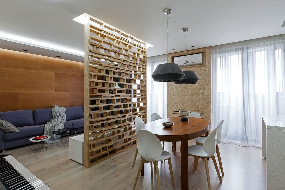 Custom plywood partition delineates living room from the dining area in this small apartment