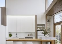 Double-height-modern-kitchen-in-white-with-wooden-shelves-217x155
