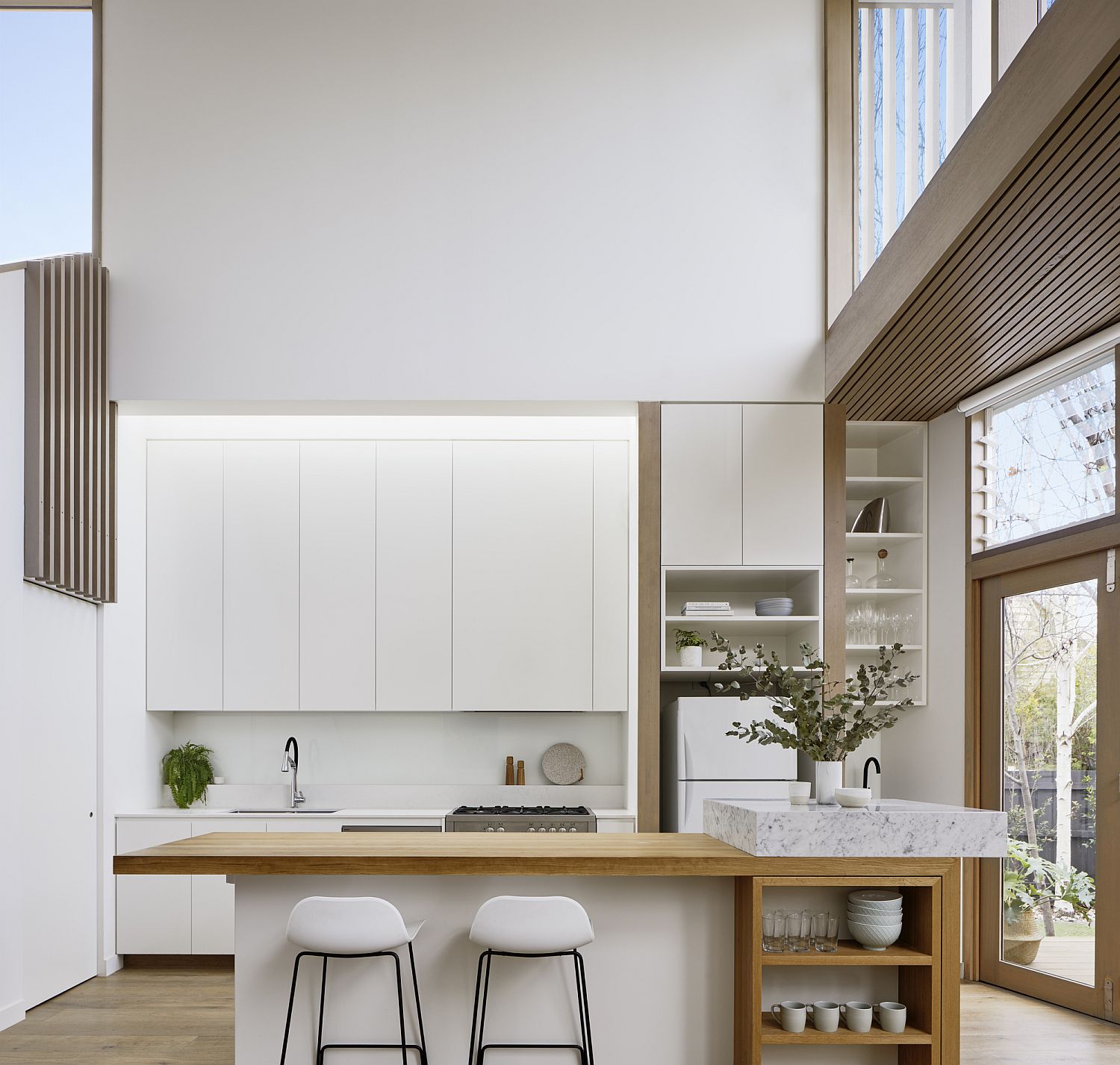 Double-height modern kitchen in white with wooden shelves
