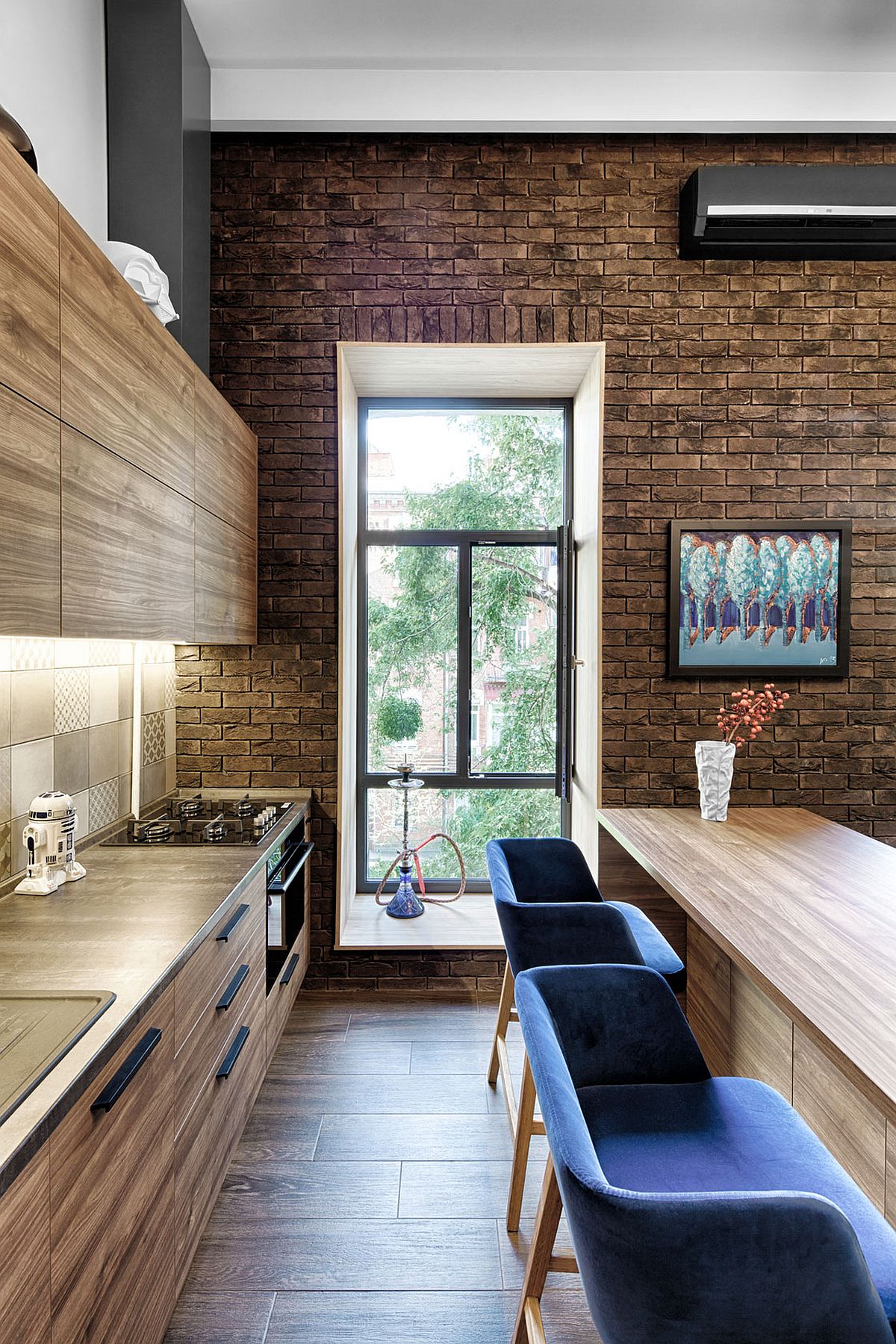 Kitchen-neatly-tucked-behind-the-living-room-and-dining-space-inside-tiny-apartment-with-brick-walls