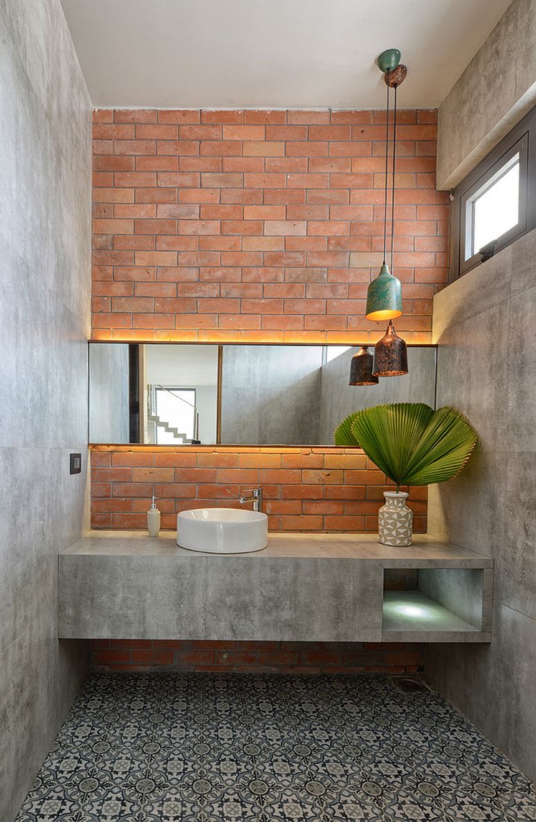 Industrial bathroom with brick accent wall is draped in concrete