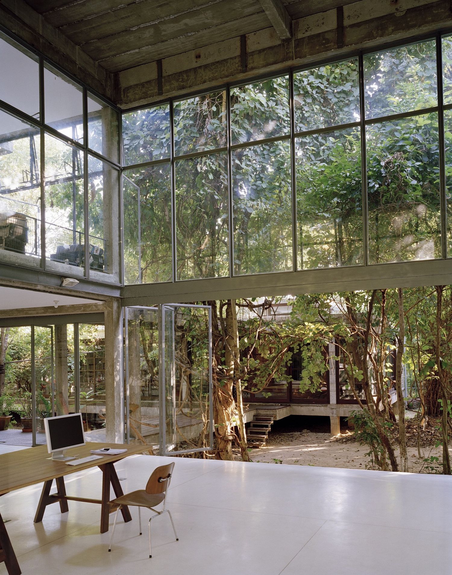 Studio and kids' play area of the home in Thailand with double height ceiling and sweeping glass windows
