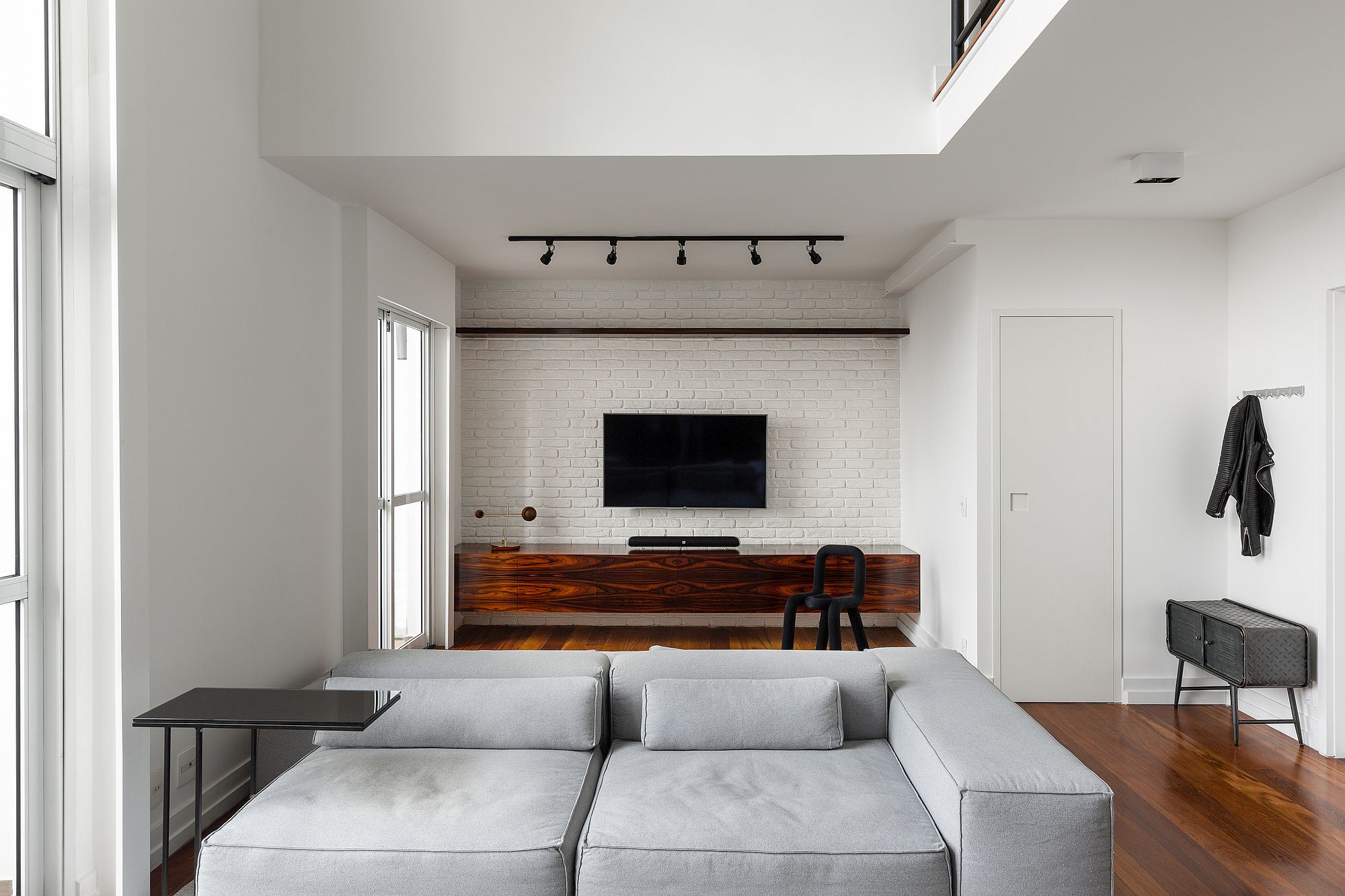 Wooden media unit stands out when placed before the whitewashed brick wall