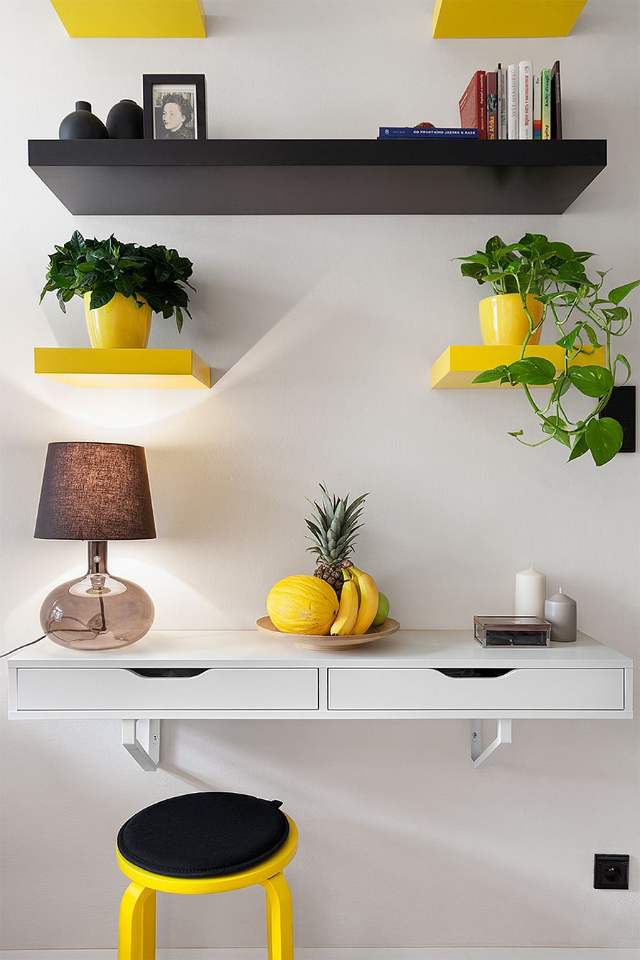 Yellow and black floating shelves act as plant holders inside this budget friendly apartment