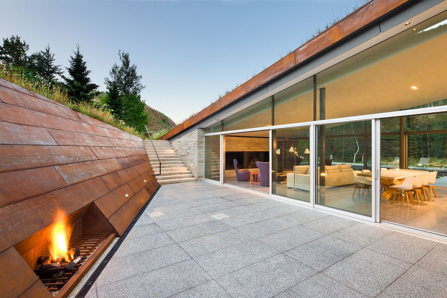 Corten clad wall for the sunken lounge inside the mountain home with green roof