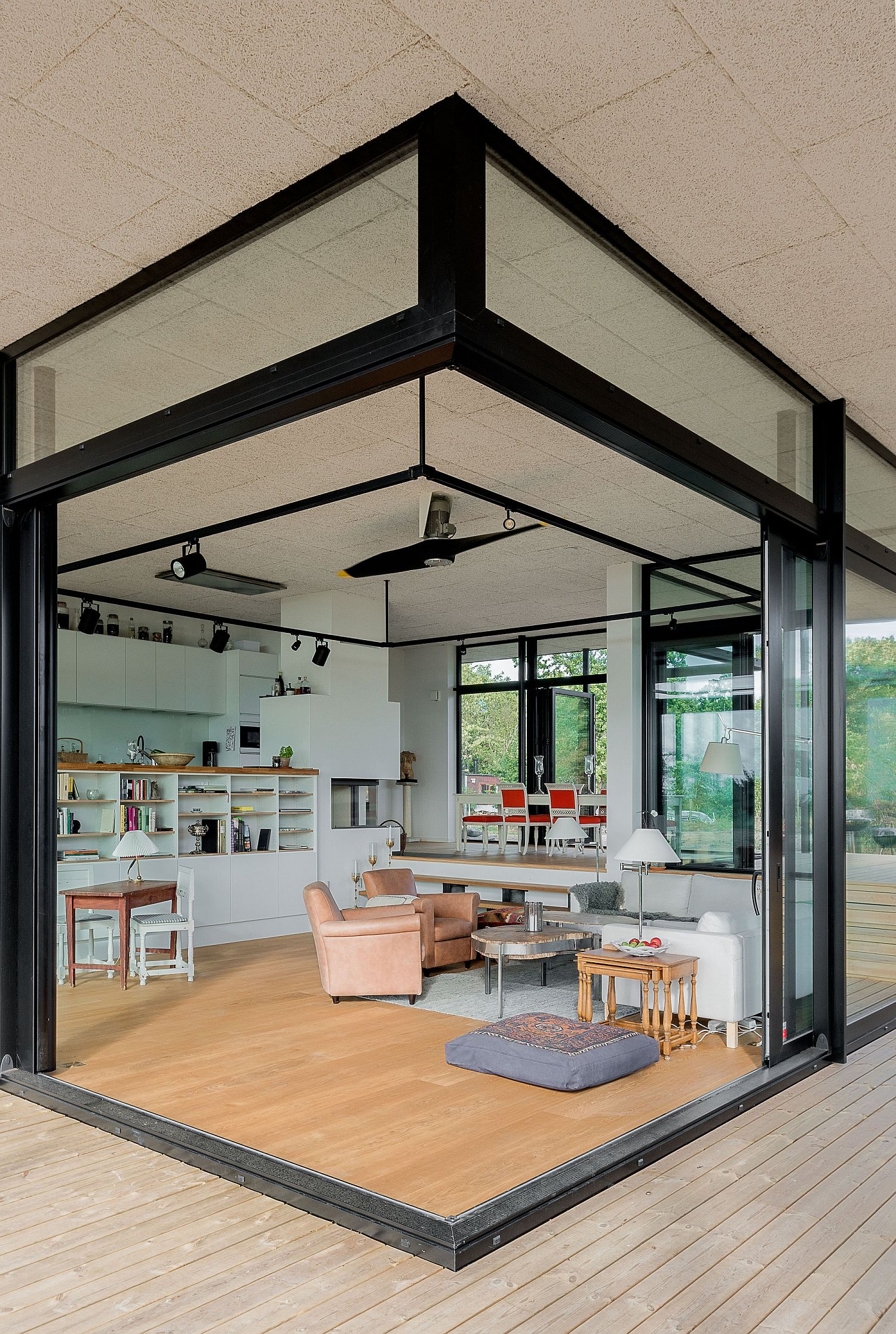 Sliding glass doors in the corner open the living room completely to the world outside