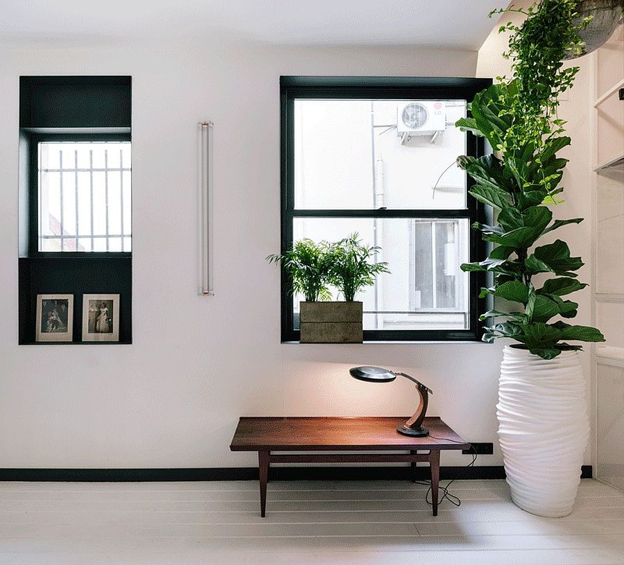 Large windows with black trims offer visual contrast in an apartment clad in white