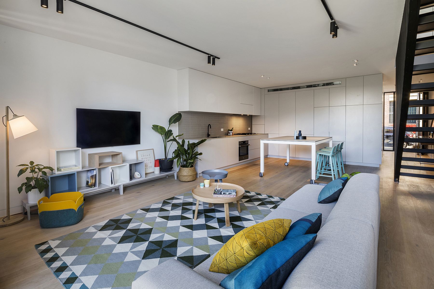 White living area with blue and yellow accents and a striking rug