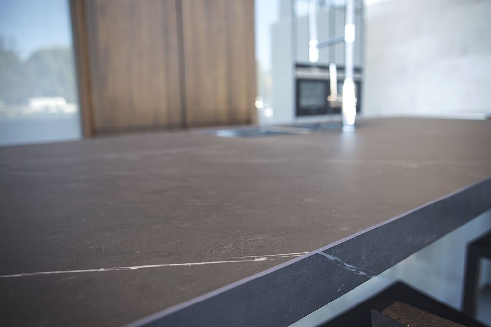 Dark kitchen island countertop with glossy grey cabinets - Porcelanosa