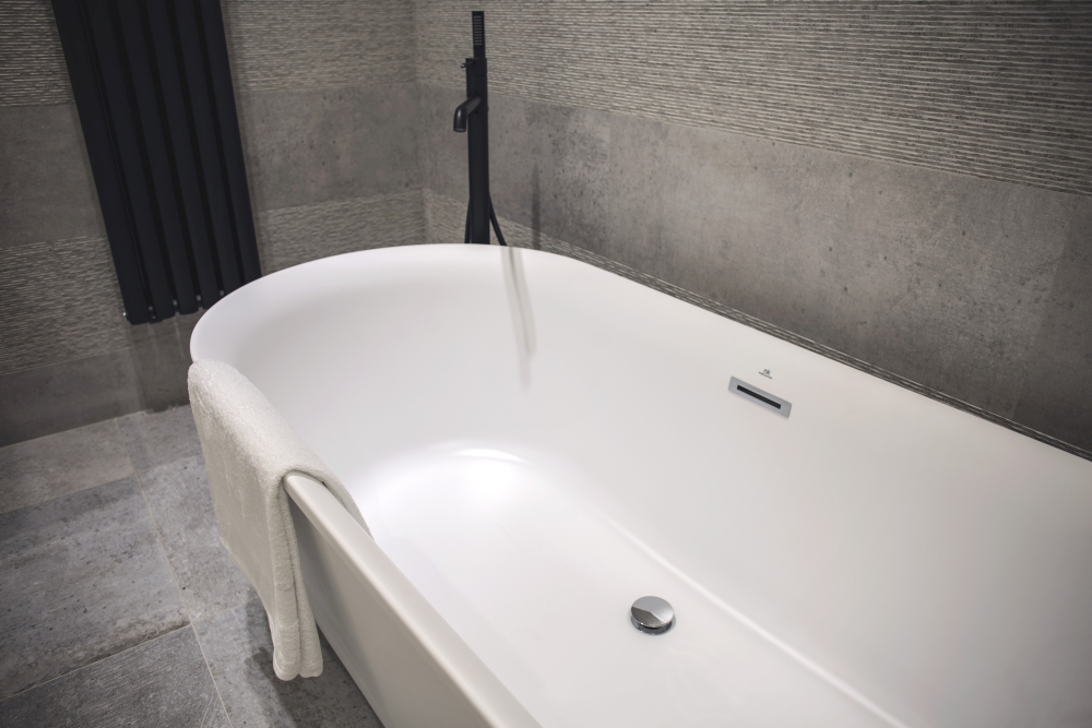Freestanding bathtub with grey stone like ceramic tiles