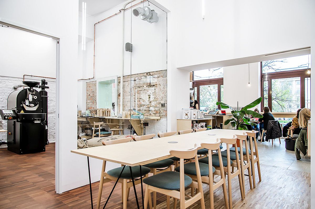 Large wooden table and plpush chairs create a smart dining and workshop area inside the coffee shop