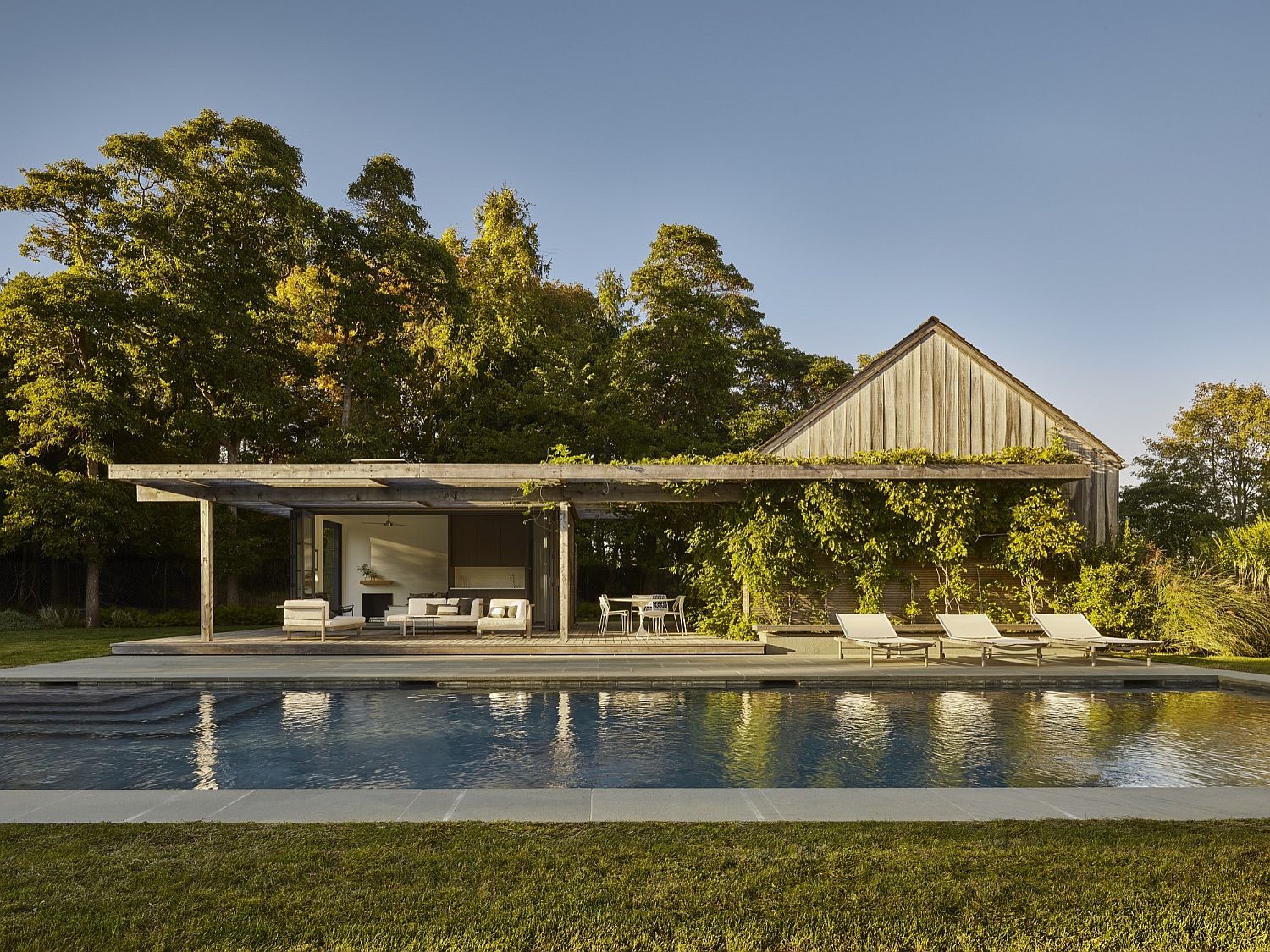 Relaxing modern pool house draped in greenery offers the perfect refuge