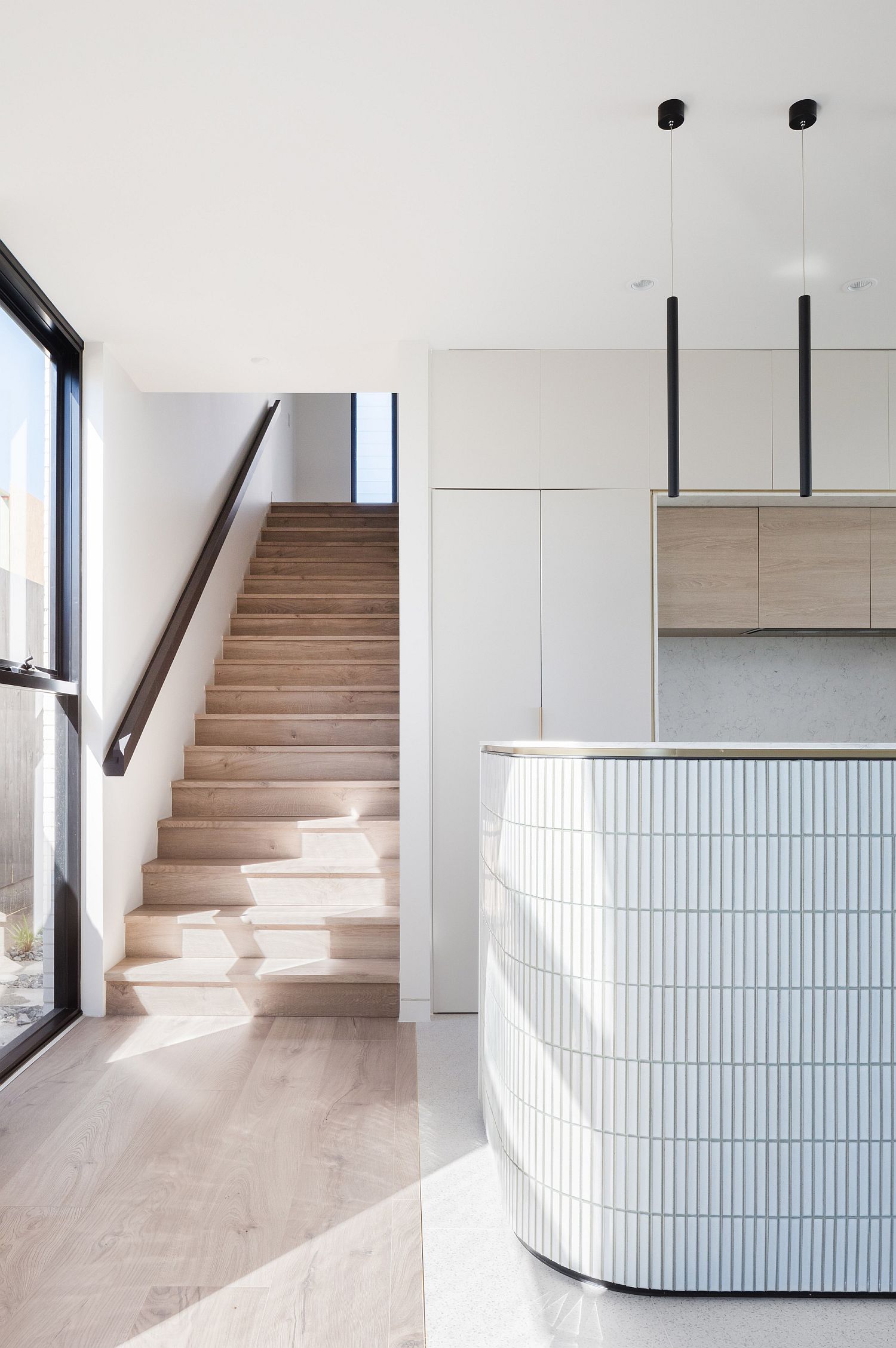 Wooden-stairway-next-to-the-curved-kitchen-island