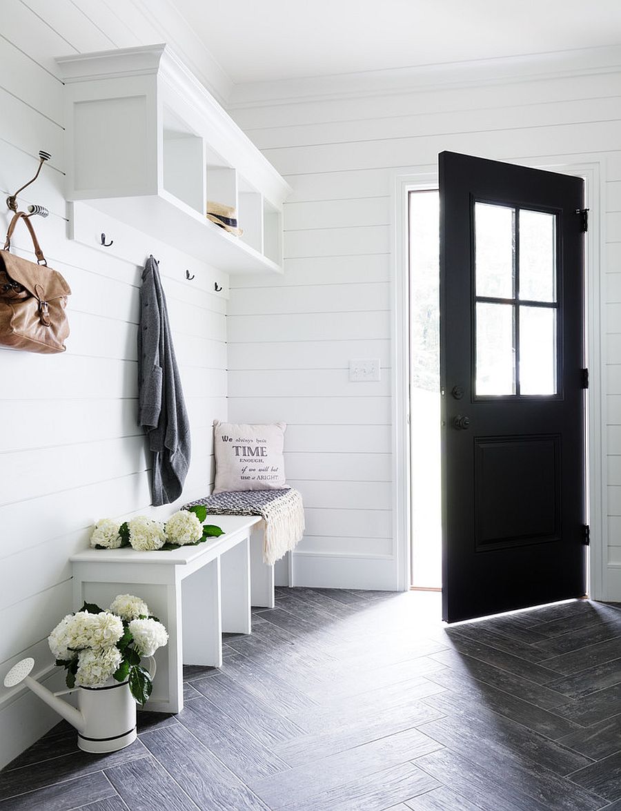 All-white mudroom with a dark door leading way