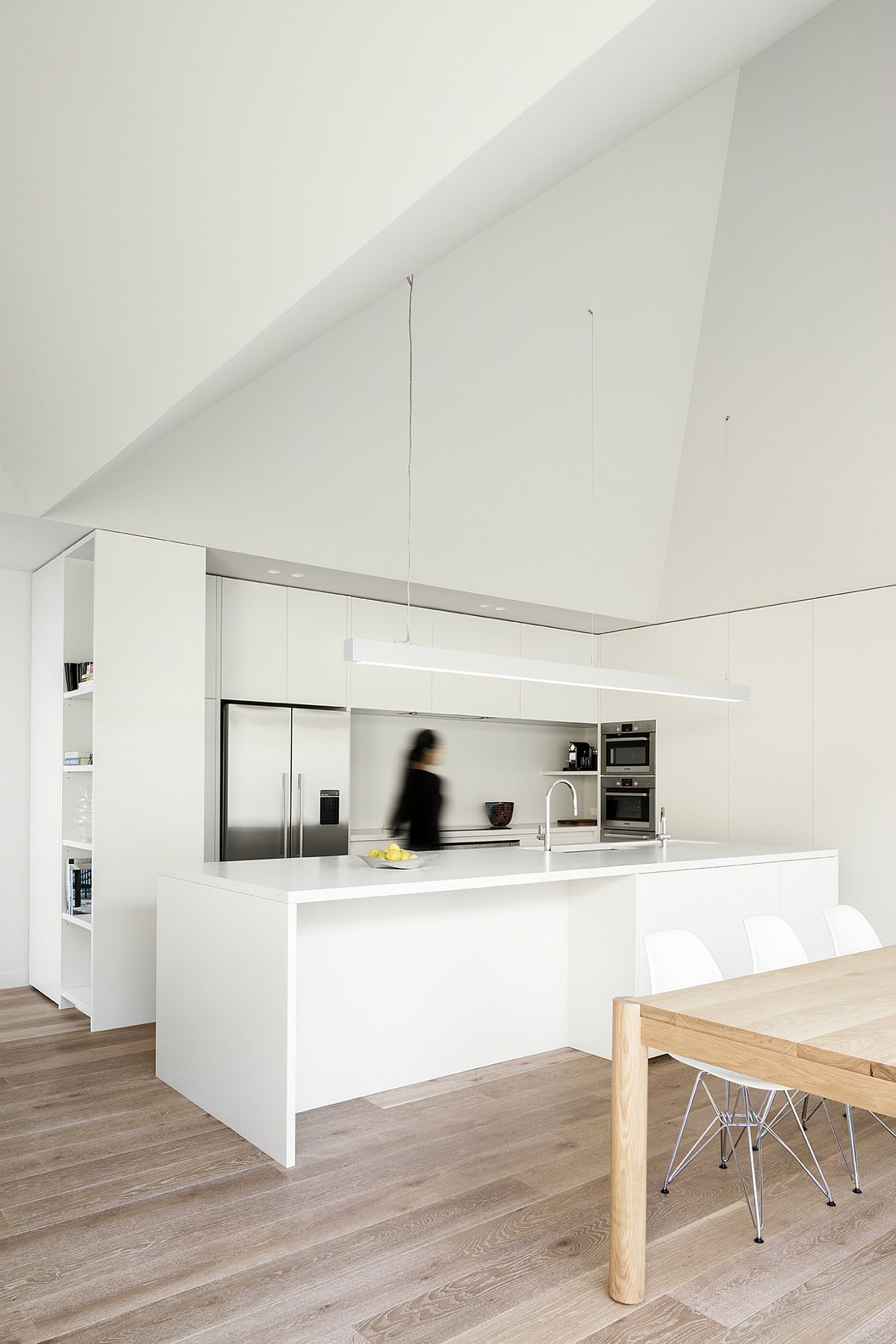 Dining table next to it brings the woodsy element to this polished corner kitchen in white