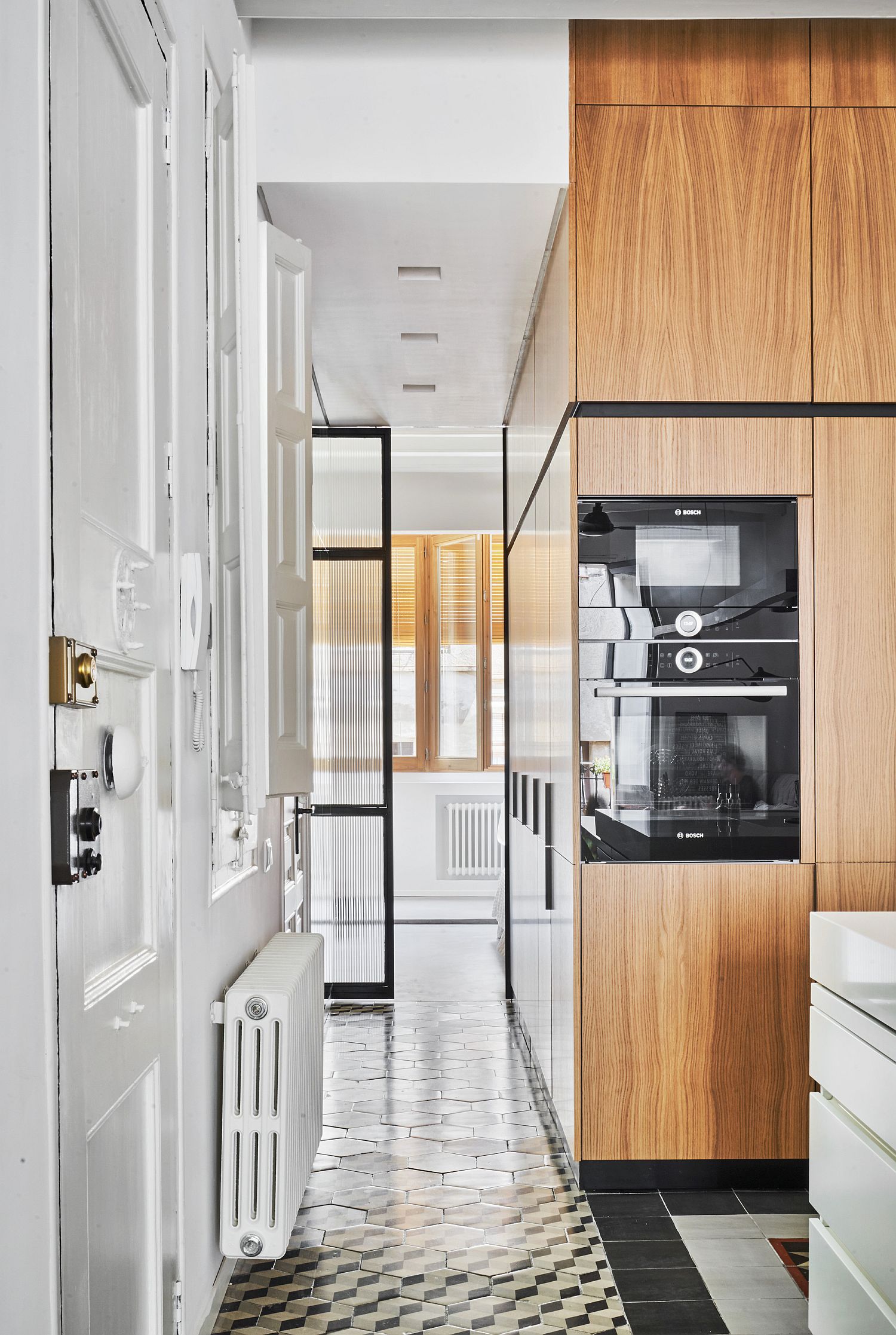 Hexagonal 3D tiles on the floor along with oak wooden cabinets in the kitchen