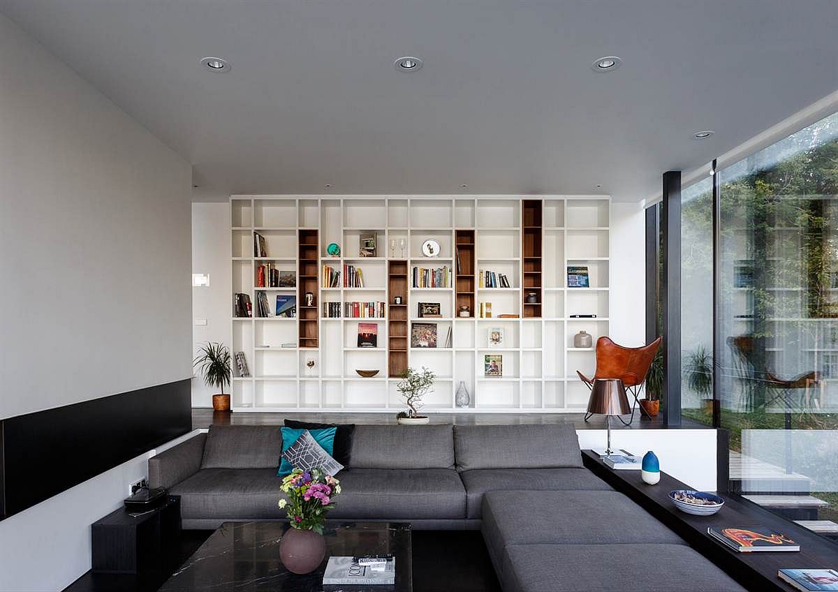 Sunken living room with large gray sectional and white bookshelf in the backdrop