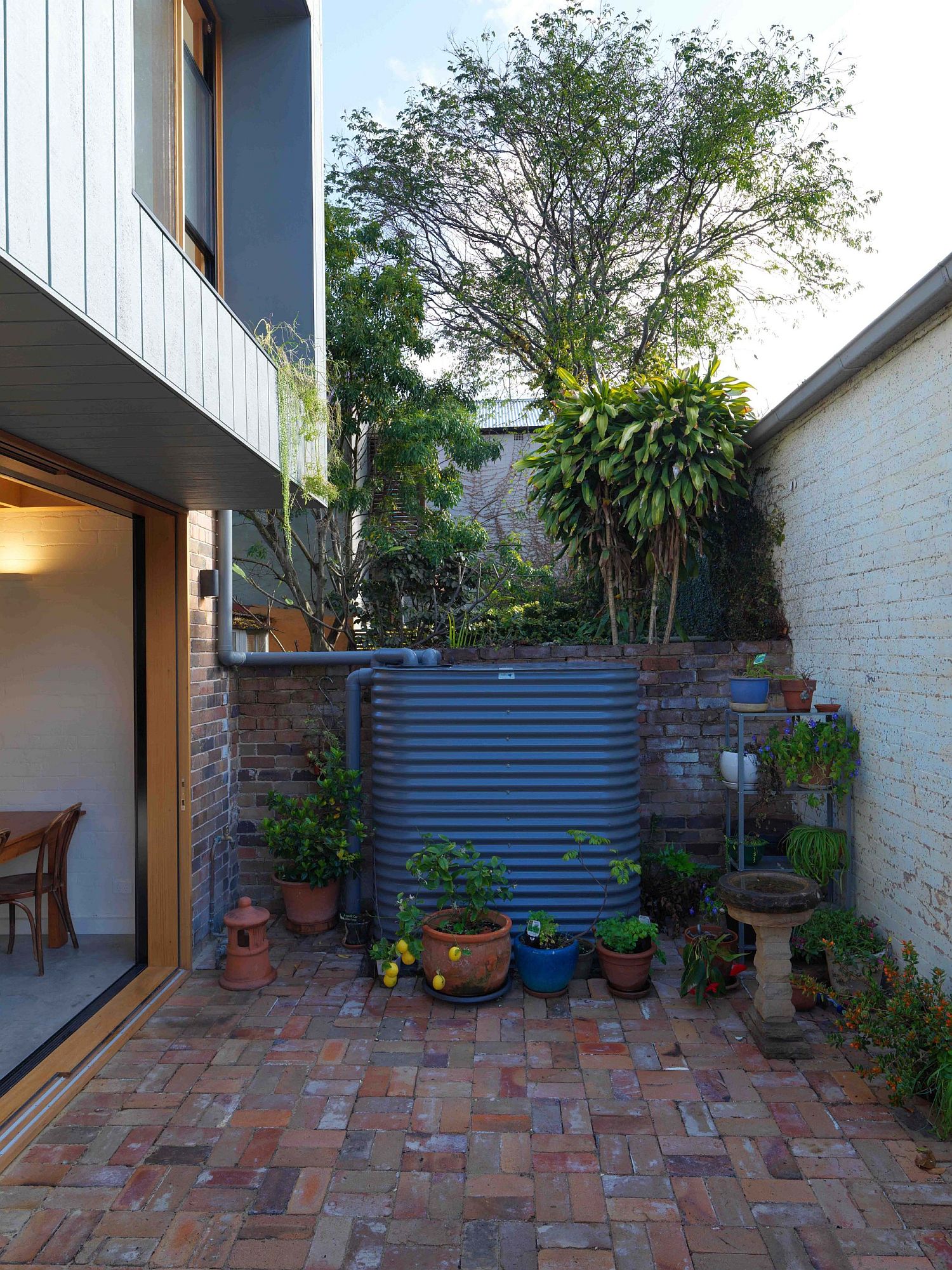 Overhang created by the rear second-level additions provides shade to the tiny backyard