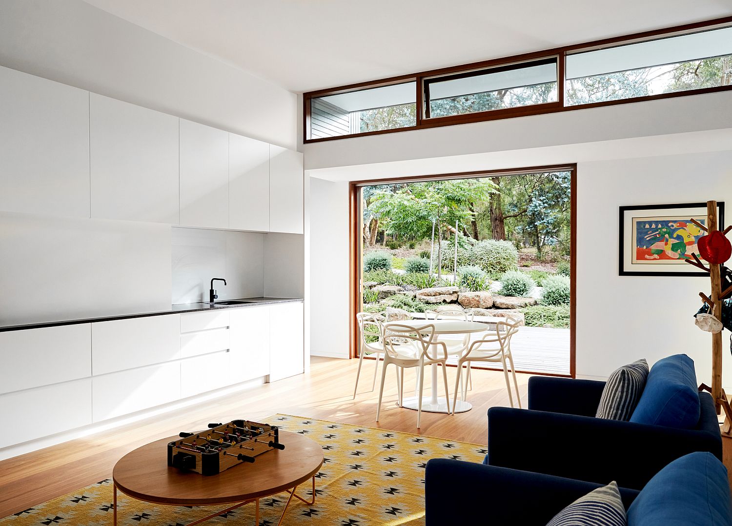 Spacious white living room with glass walls that connect it to the landscape outside