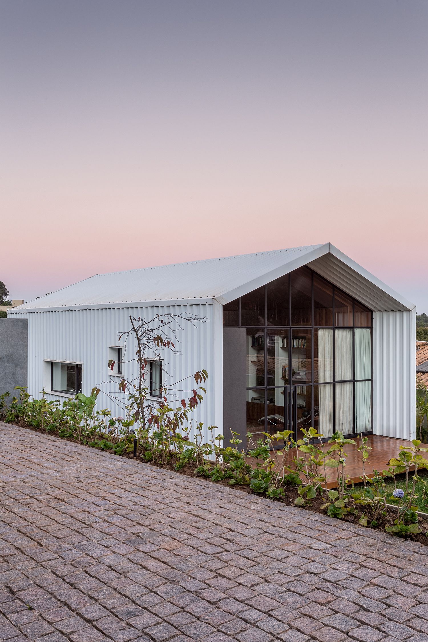 White metallic tiles cover the exterior of the backyard office