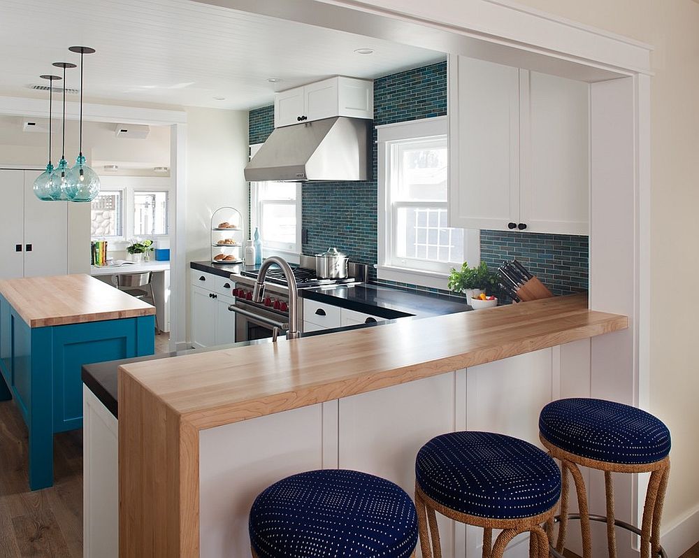 Beach style kitchen with bar stools that have blue cushions which add color to the setting