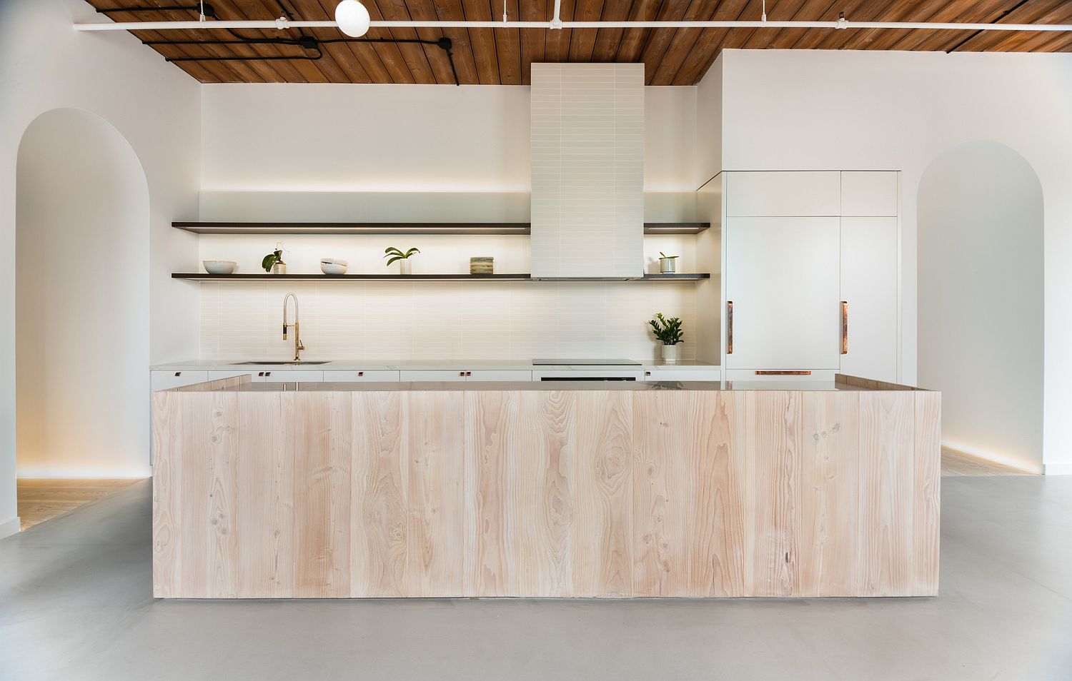 Central island of the spacious white kitchen clad in douglas fir