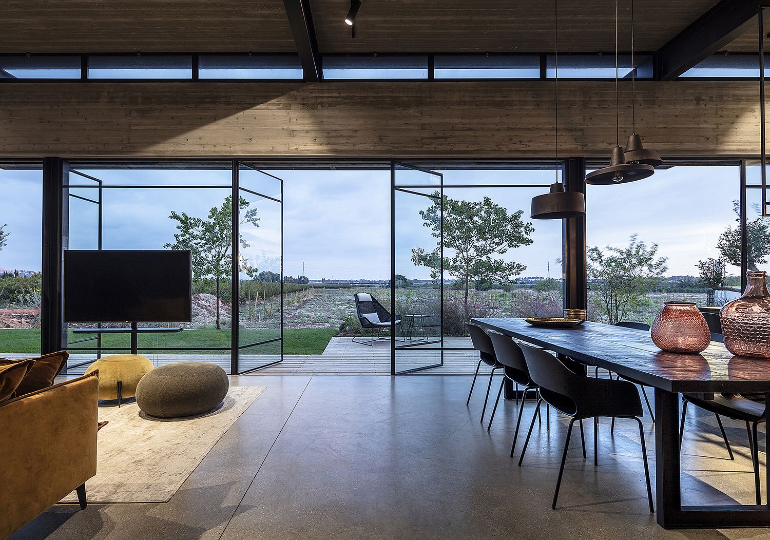 Swiveling glass doors connect the living room with the open field outside