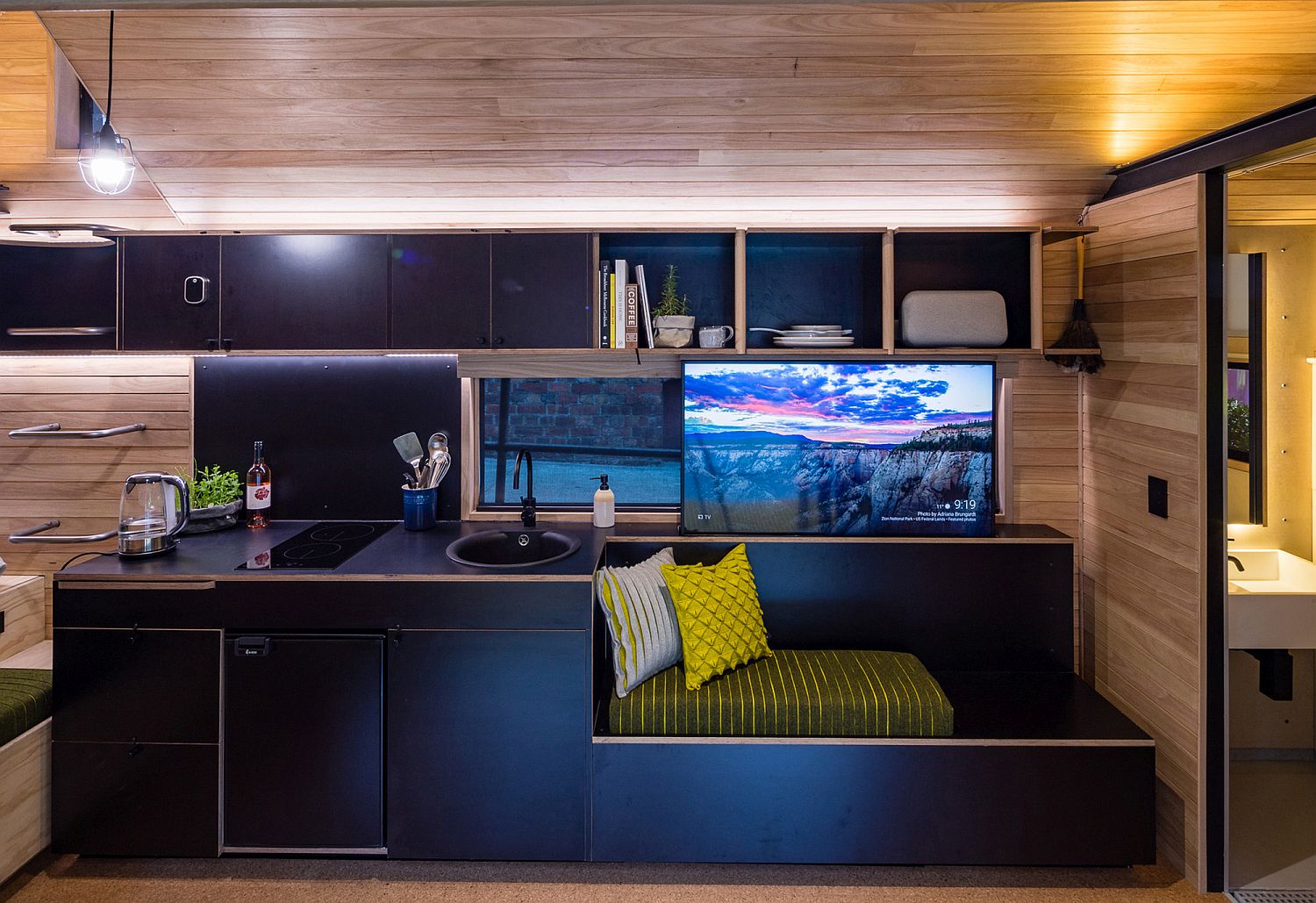 Single wall kitchen in black inside the cabin with a bench next to it