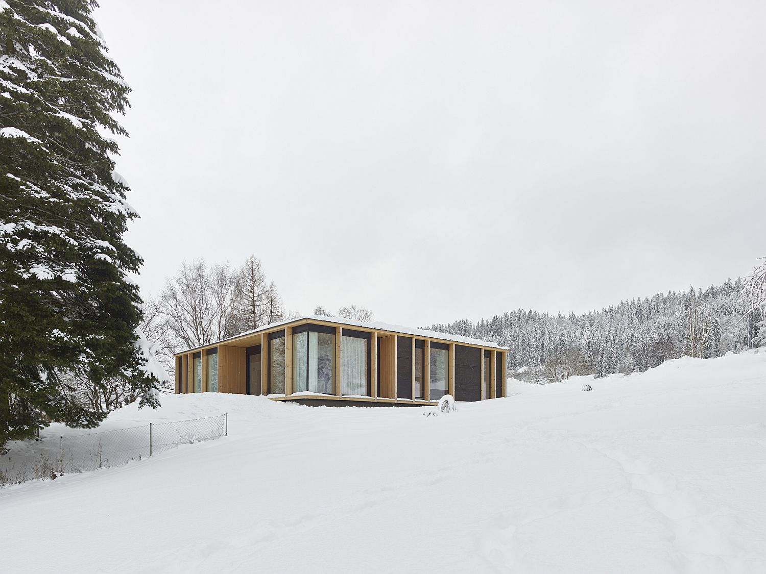 Wood and glass extreior of Austrian home in a rugged, snow-clad terrain