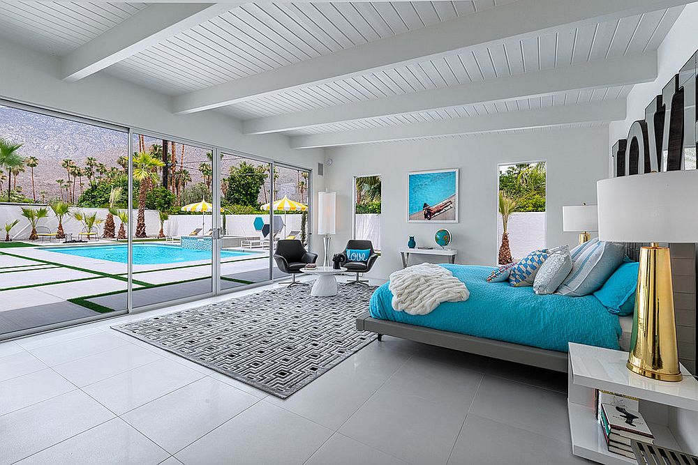 Bedding adds blue to the refined beach style bedroom connected with the pool area outside