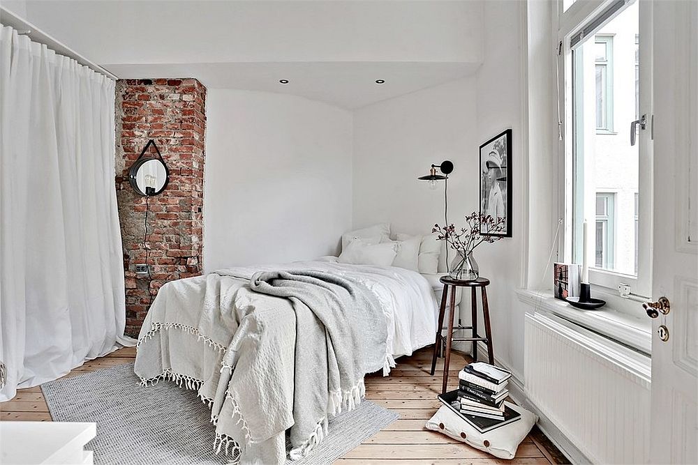 Brick wall section brings texture to the minimal bedroom in white