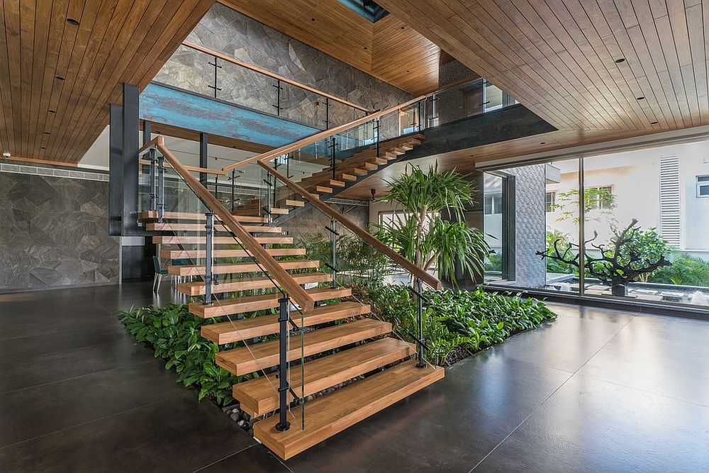 Contemporary stairway with greenery beneath it that adds ample freshness to the interior