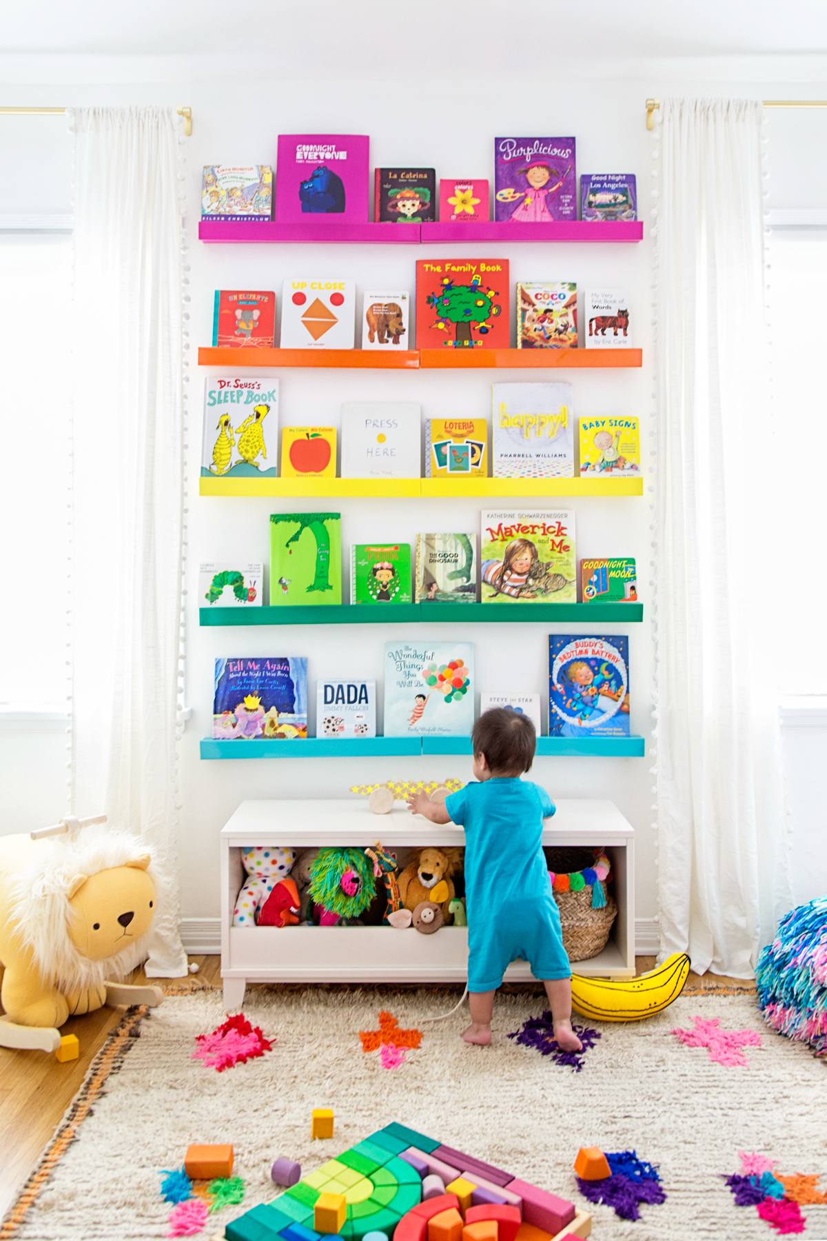 Rainbow bookshelves in a nursery designed by Studio DIY