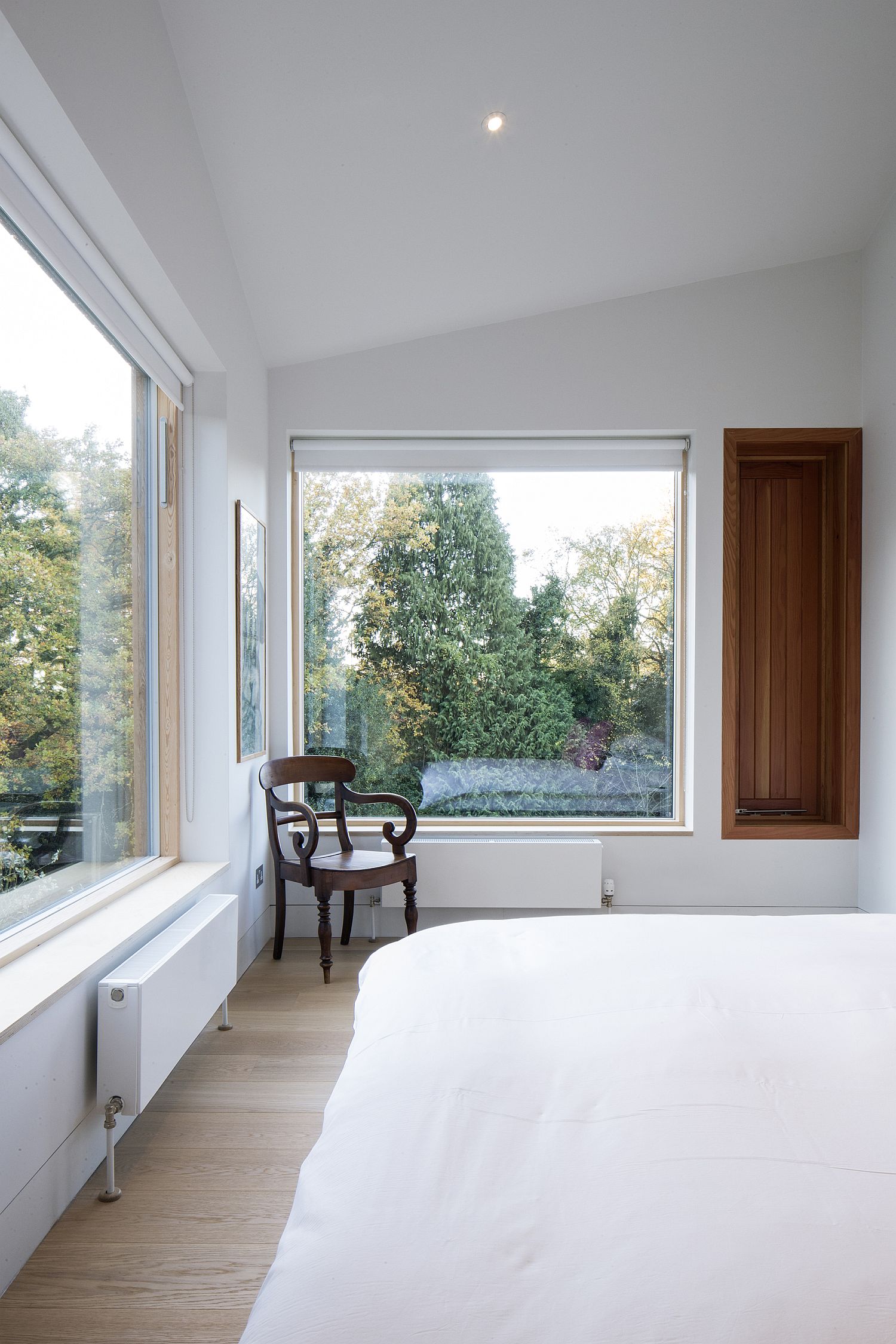Large glass windows usher ample light into the modern white bedroom