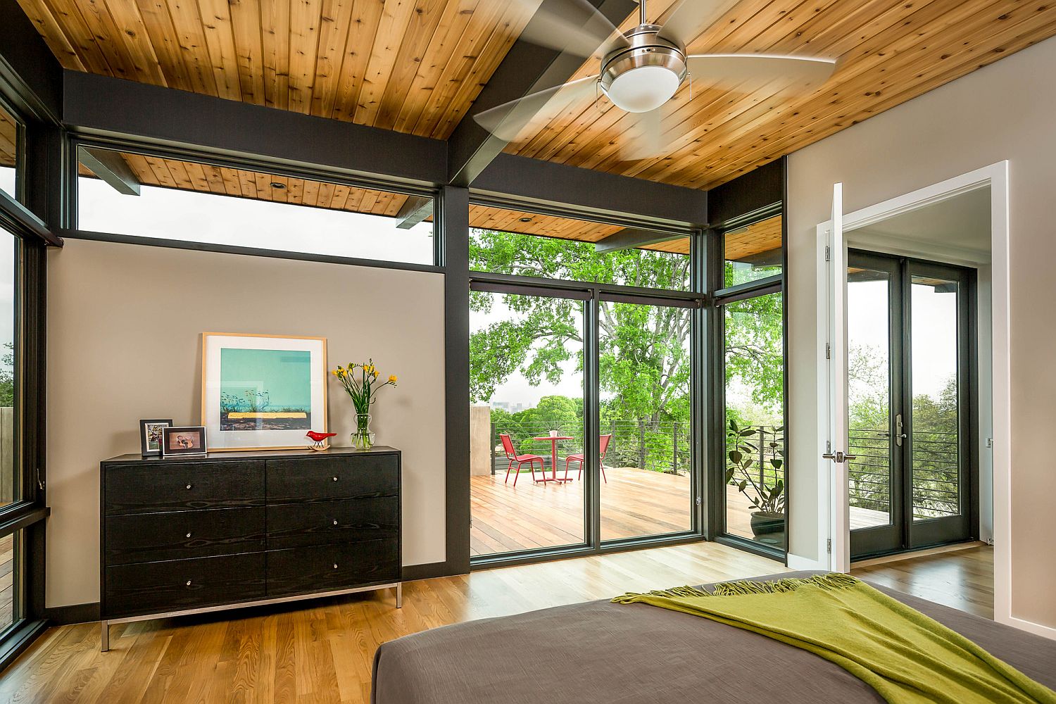 Metallic beams and wood create a cozy bedroom with many windows and glass walls